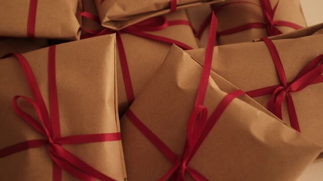 Christmas presents wrapped in brown craft paper and tied with thin red ribbon. Simple and modern wrapping aesthetics. Winter holidays gift giving tradition. Secret Santa.