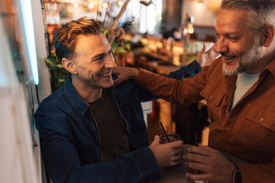 Happy male friends spending leisure time while having fun at restaurant