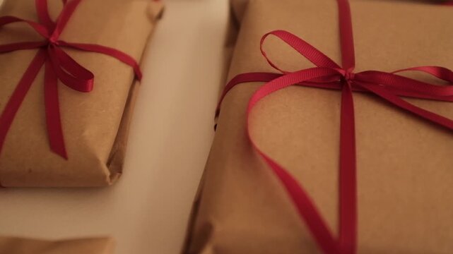 Christmas presents wrapped in brown craft paper and tied with thin red ribbon. Simple and modern wrapping aesthetics. Winter holidays gift giving tradition. Secret Santa.