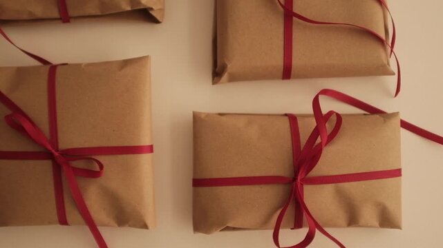Christmas presents wrapped in brown craft paper and tied with thin red ribbon. Simple and modern wrapping aesthetics. Winter holidays gift giving tradition. Secret Santa.