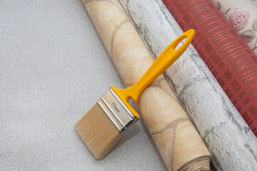 Multicolored wallpaper and a brush on a textured background. Copy space. Home or apartment renovation concept