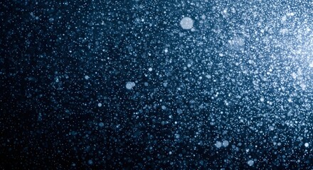 Abstract dark blue background with numerous sparkling particles resembling a starry night sky or dust in light.