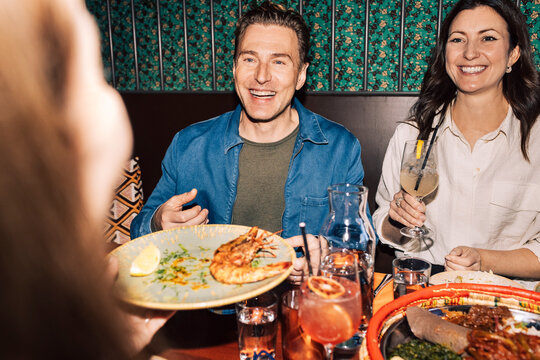 Happy male and female friends enjoying traditional Ethiopian dinner at restaurant