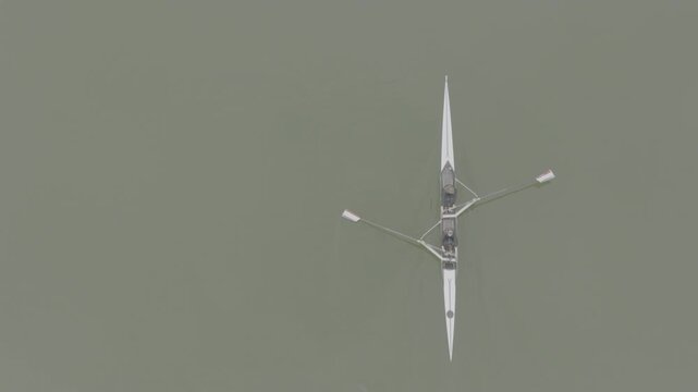 Two athletes rowing a sculling boat on calm water, teamwork and endurance in competitive sport. Practicing sport rowing. Rowers in a racing boat row in slow motion video. ProRes 422 10 bit D-Log.