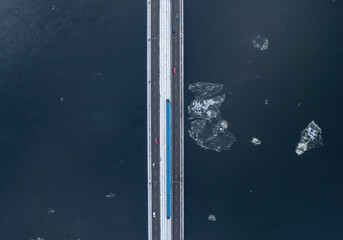 Aerial top-down view of a metro bridge over a frozen river.
