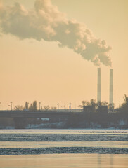 Industrial smokestacks emitting thick smoke into the grey sky.