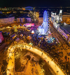 Aerial drone view of a festive Christmas market with a large illuminated tree.