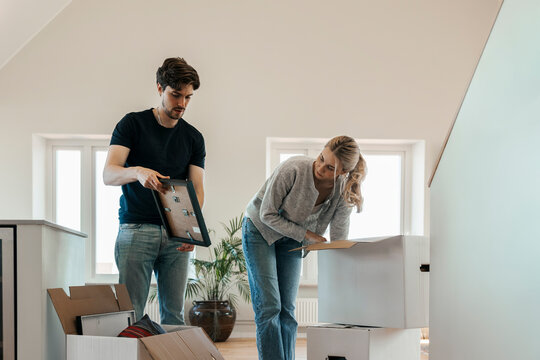 Young couple examining things to be arranged from cardboard boxes during home improvement