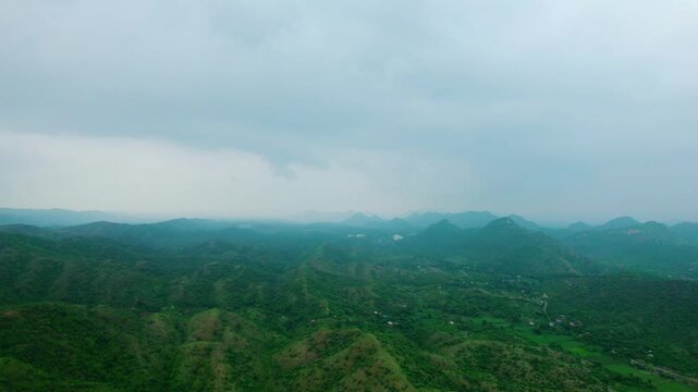 4K aerial view of Lush green Rayta Hills in Aravalli Range at Udaipur, Rajasthan, India. Green mountains and cloudy sky during monsoon season. Travel and holidays background. Protect ecology, save env