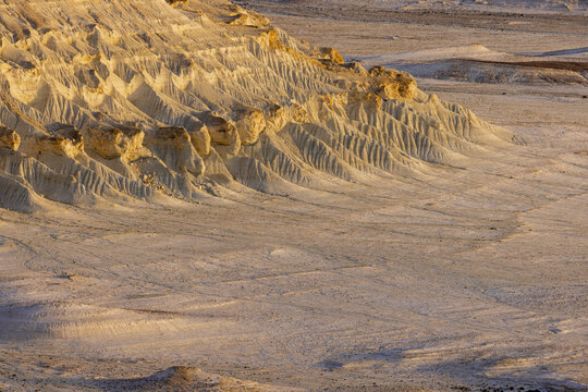 View of the textured, sandy landscape with stark white and yellow formations, etched by wind and time, creating a surreal, otherworldly vista, Bozhira, Mangystau Region, Kazakhstan.
