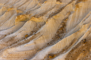 View of layered, eroded earth formations, sculpted by time and elements into ridges and valleys, bathed in the warm glow of the setting sun, Bozhira, Mangystau Region, Kazakhstan.