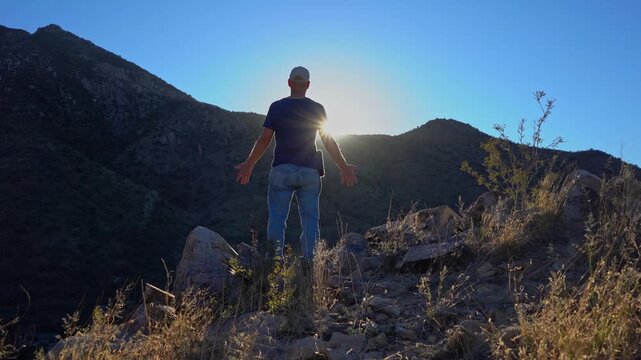 A man on a mountain top in awe with sun flare