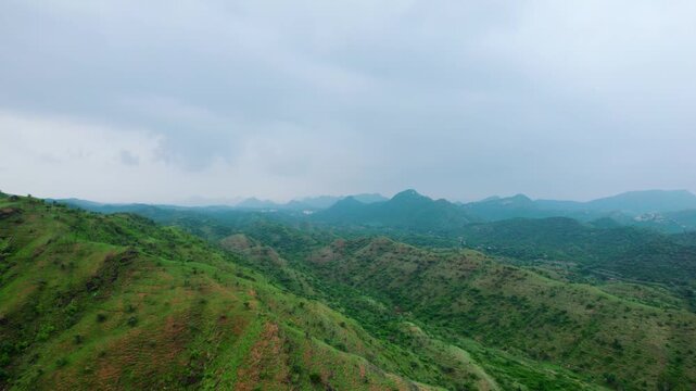 4K Aerial shot of Aravalli range as seen from Rayta in Udaipur, Rajasthan. Green landscape during monsoon season and dark storm clouds in sky. Travel and holidays background. Lush green hills of Arava