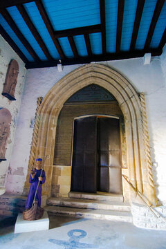 View of an arched doorway and a statue of a fisherman in a basket under a blue ceiling with white walls, Capbreton, France.