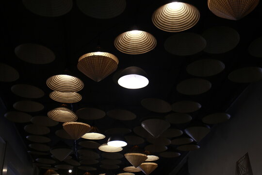 Traditional Vietnamese conical hats are used as decorative items and hanging lamps in interior spaces.