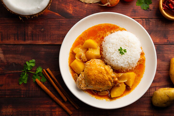 Massaman Curry with chicken and cooked rice in white plate.Cooked chicken meat and potatoes groundnut with massaman curry paste in coconut milk.asian food.Top view.