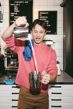 Professional male barista showing coffee making skills in cafe