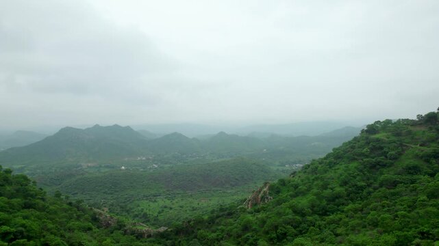 Rayta hills in Aravalli mountain range of Udaipur, Rajasthan, India. 4K Aerial view of a lush green hills of Aravalli Range. Dark clouds in sky during monsoon season.