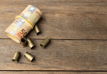 Used old ammunition casings with brazilian real bills with copy space