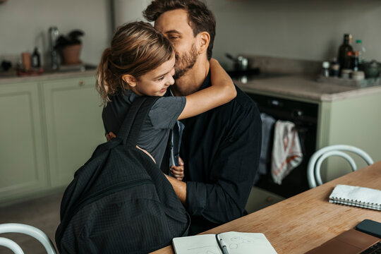 Father kissing daughter coming back from school at home