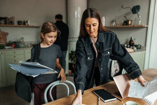 Mother making space for daughter on table at home