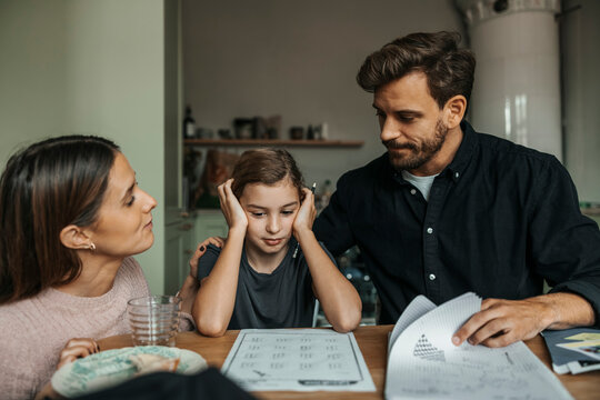 Parents consoling daughter facing difficulty while doing homework at home