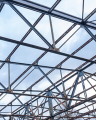 Fototapeta premium Metal framework of a disassembled building under a cloudy sky in an urban area