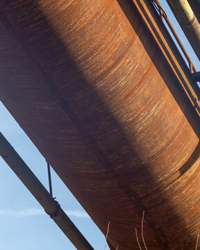 Weathered industrial pipe against a clear blue sky in an urban setting