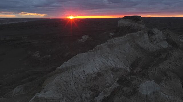 Aerial view of the rugged, layered terrain of Airakty Castle, bathed in the warm glow of the setting sun, Shetpe, Mangystau Region, Kazakhstan.