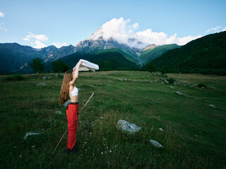 Naklejka premium Girl outdoor scene in mountains field, exploring nature and landscape under blue sky with clouds, breeze over grass and distant peaks, casual clothing and adventure