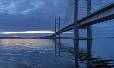 Sunrise over a modern cable-stayed bridge reflecting on still water