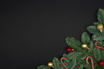 Evergreen Fir Branches with Christmas Ornaments and Candy Canes on Dark Background with Copy Space