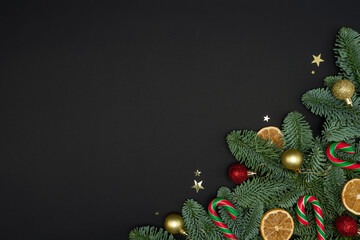 Evergreen Fir Branches with Dried Orange Slices, Christmas Ornaments and Candy Canes on Dark Background with Copy Space