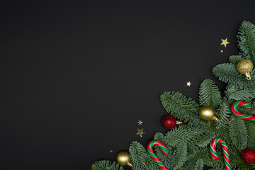 Evergreen Fir Branches with Christmas Ornaments and Candy Canes on Dark Background with Copy Space