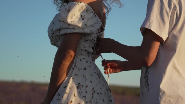 Couple lacing dress corset in lavender field at sunset romantic intimate moment outdoors