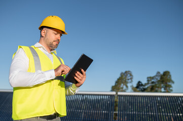 Technician using tablet to check photovoltaic system outdoors