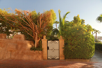 A gate to a private house surrounded by dense green trees and bushes.