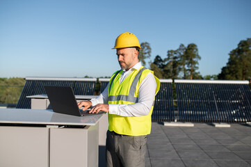 Technician using computer to monitor solar power system efficiency