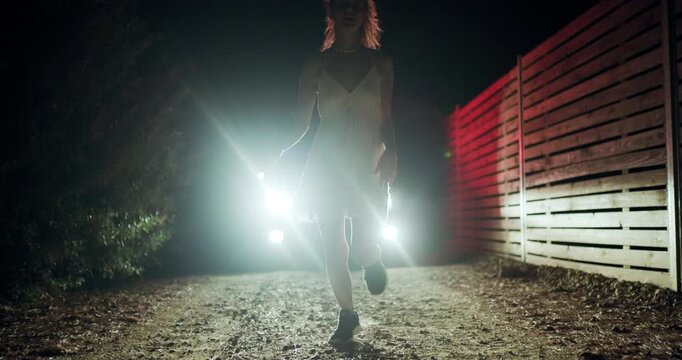 Girl fleeing from police silhouette on a dark street at night while the car lights create an intense atmosphere