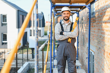 Confident builder holding spirit level on construction site