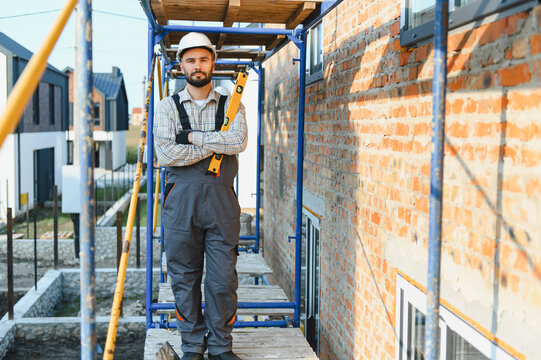 Construction worker holding spirit level on building scaffolding