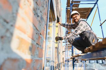 Construction worker using level tool for window installation