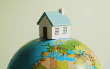 Small Model House Sitting on Top of Earth Globe for Global Real Estate