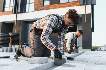 Construction workers installing paving stones on urban sidewalk