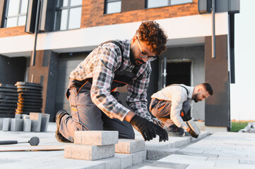 Construction workers installing paving stones on urban sidewalk