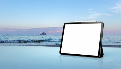 Digital tablet with a blank white screen and stylus pen on a reflective surface. Scenic beach and ocean sunset background, ideal for travel apps, remote work, and outdoor lifestyle concepts