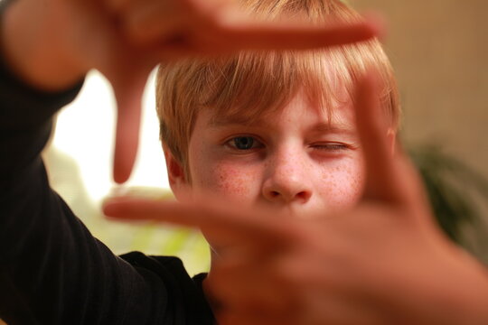 Young boy framing vision with hands, focusing on future