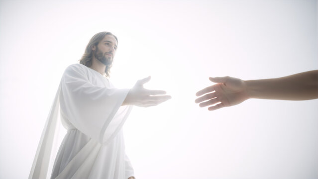 Jesus Christ reaching out a helping hand to a human hand. Divine light background. Religious concept of salvation and faith