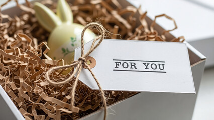 Minimalist Easter gift box with a bunny figurine and a personal tag for holiday present ideas.