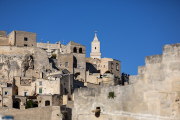 panoramic view of the ancient sassi di matera limestone buildings carved into the hillside under a clear blue sky in basilicata southern italy